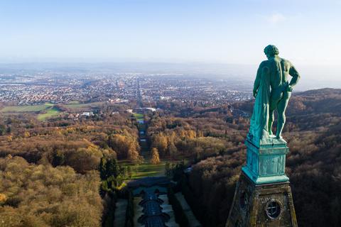 Der Herkules, eine Kupferstatue, steht im UNESCO-Weltkulturerbe Bergpark Wilhelmshöhe vor dem Panorama der Stadt Kassel.