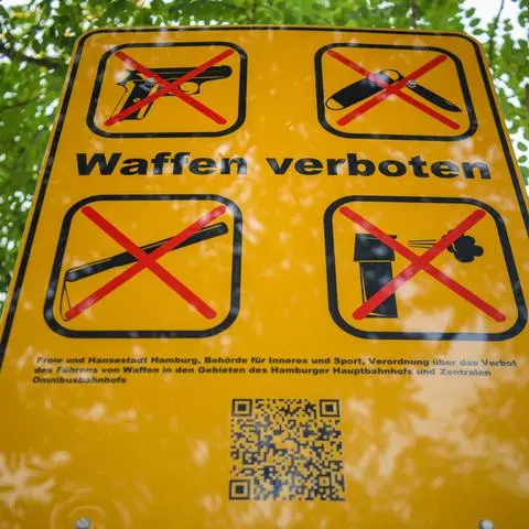 Ein Schild („Waffen verboten“) informiert mit Piktogrammen über eine Waffenverbotszone. (Symbolfoto